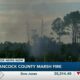 Firefighters work to put out a Hancock County marsh fire